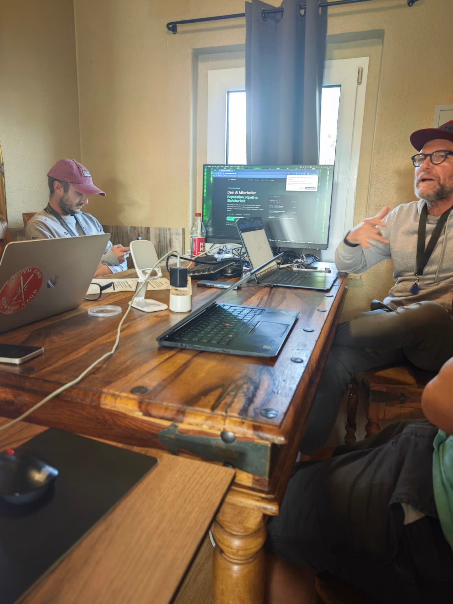 Gespräch am Arbeitstisch zwischen Laptops und Monitoren
